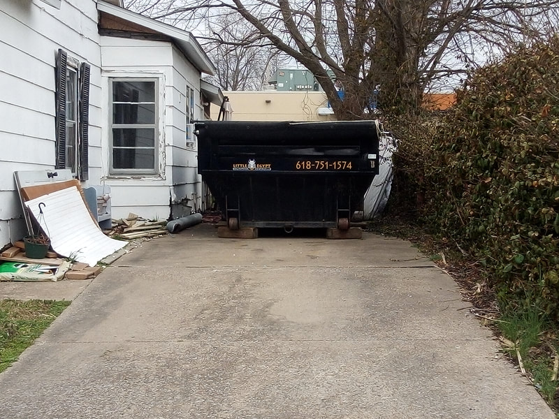 front-of-13-yard Little Egypt dumpster on a paved driveway beside a house